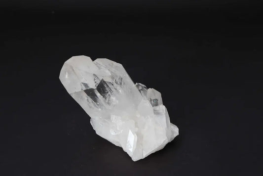 Clear Quartz Cluster on dark background, showcasing multiple crystal points for energy purification and amplification.