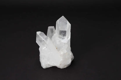 Clear quartz cluster on black background, showcasing its natural crystal points and light-amplifying properties.