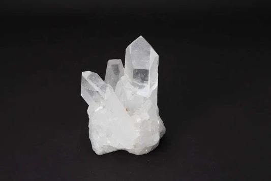 Clear quartz cluster on black background, showcasing its natural crystal points and light-amplifying properties.