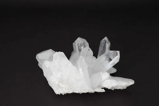 Clear Quartz Cluster with multiple crystal points on a dark background, radiating clarity and high vibrational energy.