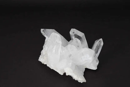 Clear Quartz Cluster on dark background showcasing its crystal points and energy amplifying properties.