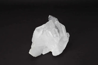 Clear Quartz Cluster on dark background, showcasing natural crystal formations and points radiating energy and light.