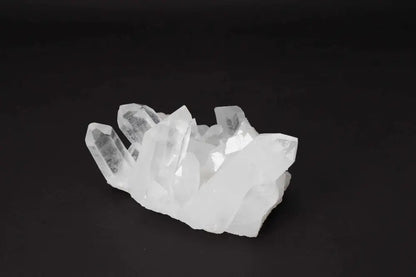 Clear Quartz Cluster on black background radiating clarity and high vibrational energy, featuring multiple crystal points on a shared matrix.