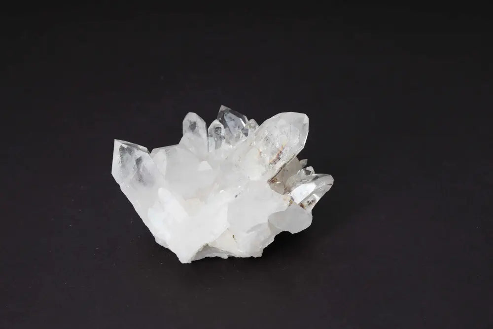 Clear quartz cluster on black background, showcasing multiple crystal points for energy amplification and purification.