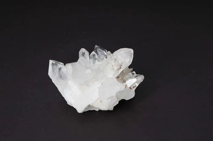Clear quartz cluster on black background, showcasing multiple crystal points for energy amplification and purification.