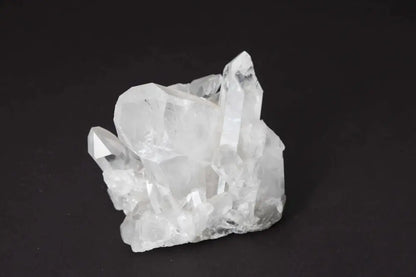 Clear Quartz Cluster on dark background, showcasing natural crystal formations and high vibrational energy for space harmony.