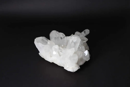 Clear Quartz Cluster on dark background, showcasing radiant clarity and energy amplification with multiple crystal points.