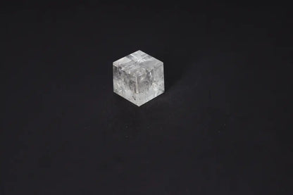 Clear Quartz Cube 3.5 cm on black background, known for purification and neutralizing negative vibrations and electromagnetic radiation.