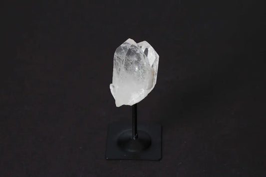 Clear Quartz Crystal on Metal Stand, enhancing mental clarity and emotional stability, from Sylvia Crystals against a dark background.
