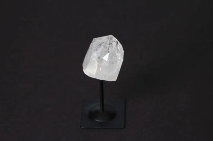 Clear Quartz crystal on a sleek metal stand against a dark background, showcasing its luxurious and spiritual essence.