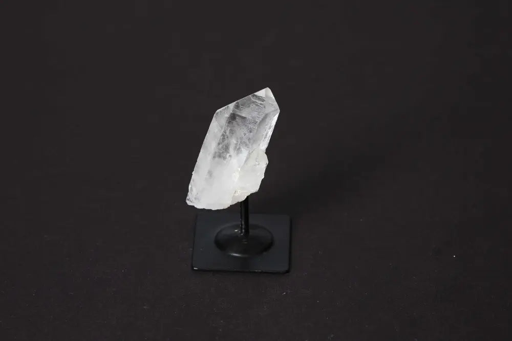 Clear Quartz crystal elegantly displayed on a sleek metal stand against a dark background, showcasing its natural beauty and clarity.