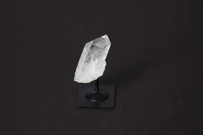 Clear Quartz crystal elegantly displayed on a sleek metal stand against a dark background, showcasing its natural beauty and clarity.