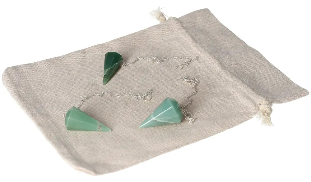 Three green quartz pendulums on a beige pouch for meditation and crystal healing practices.