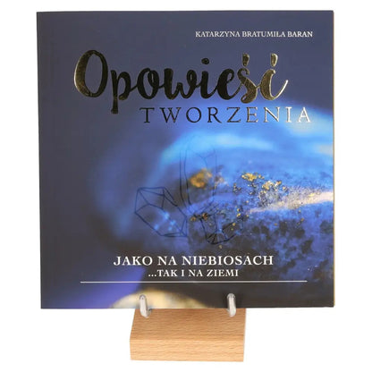Cover of the book 'Opowieści Tworzenia' with a blue-themed design on a wooden display stand.