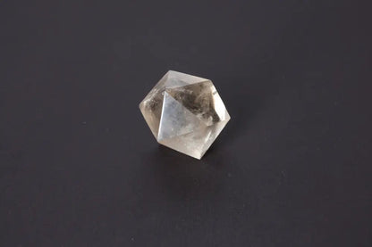 Clear geometric crystal with angular facets reflecting light on a dark background.