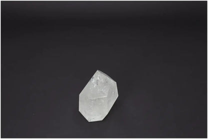 Clear Lemurian Quartz Obelisk on dark background, enhances energy and aligns chakras, spiritually supporting with unique quartz properties.