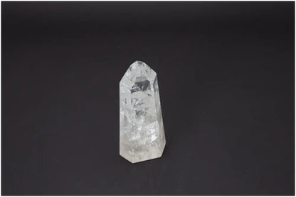 Clear Lemurian Quartz Obelisk against a dark background, known for its unique energetic properties and associations with chakras and zodiac signs.