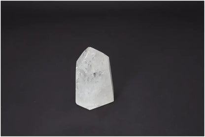 Lemurian Quartz Obelisk with spiritual energy properties, supports chakras and zodiac signs, clear crystal against black background.