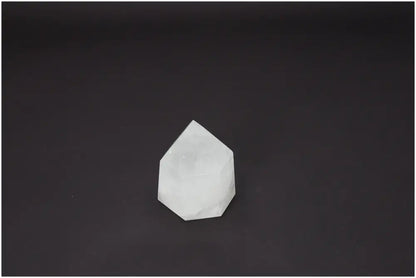 Clear Lemurian Quartz obelisk against a black background, showcasing its unique spiritual properties and chakra energies.
