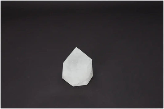 Clear Lemurian Quartz obelisk against a black background, showcasing its unique spiritual properties and chakra energies.
