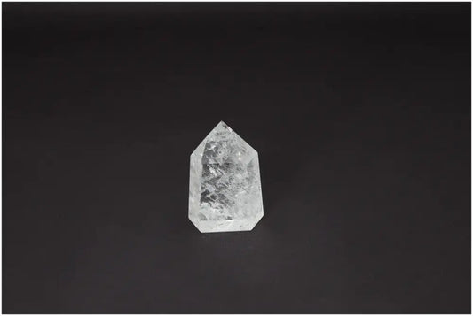 Lemurian Quartz Obelisk on a dark background, exhibiting clear crystal properties, associated with chakras and energetic healing.