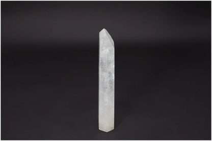 Lemurian Quartz Obelisk - clear crystal standing against dark background, symbolizing clarity and personal growth.