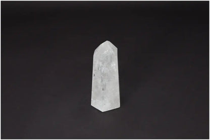 Lemurian Quartz Obelisk for clarity and balance, ethically sourced clear quartz crystal against a dark background.