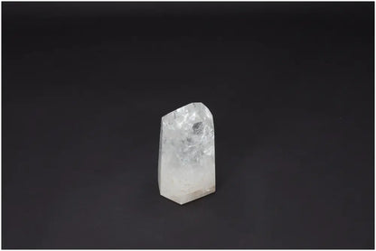 Clear Lemurian Quartz Obelisk on dark background, known as "Master Healer," amplifies energy and promotes clarity and balance.