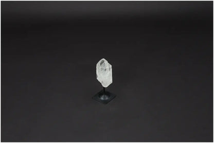 Lemurian Quartz crystal on metal stand, known for clarity and balance, displayed against a dark background.