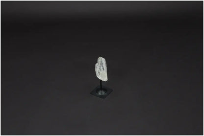 Lemurian Quartz crystal on sleek metal stand, known for clarity and healing, against a dark backdrop.