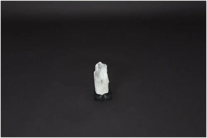 Lemurian Quartz on metal stand, a powerful Clear Quartz crystal for purification and harmonizing energy, against a dark background.