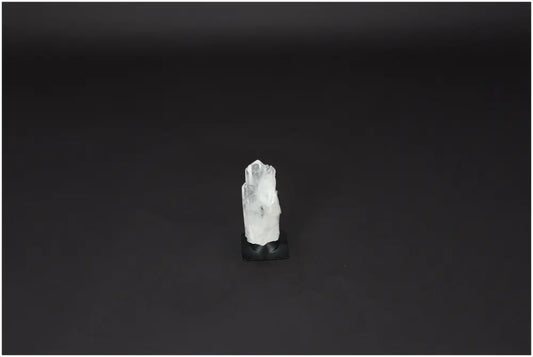Lemurian Quartz on metal stand, a powerful Clear Quartz crystal for purification and harmonizing energy, against a dark background.