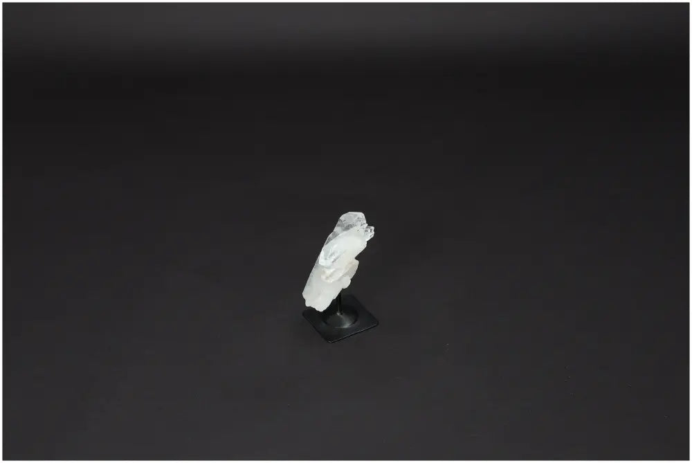 Lemurian Quartz on metal stand, known for purification and neutralizing negative energy, displayed against a dark background.
