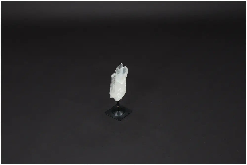 Lemurian quartz crystal on metal stand, used for purification and harmonizing energy, with sleek black background.