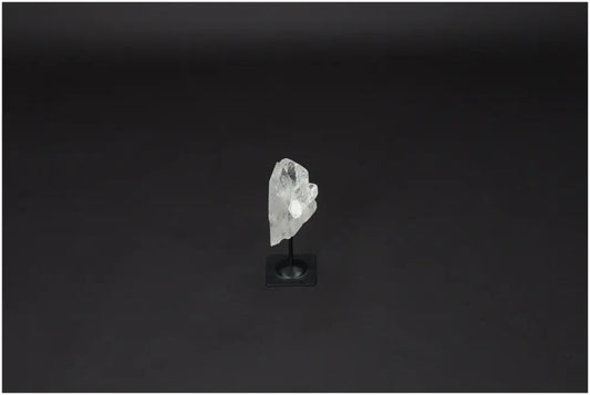 Lemurian Clear Quartz on a metal stand against a dark background, known for purification and neutralizing negative energy.
