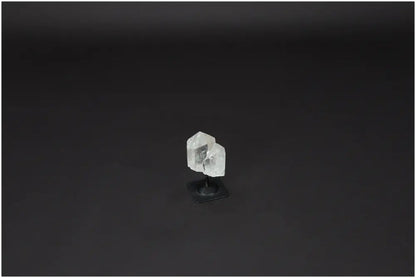 Lemurian Quartz crystal on metal stand against a dark background, known for harmonizing energy and neutralizing negative vibrations.