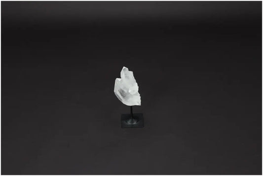 Lemurian Quartz crystal on a metal stand against a dark background, known for its purification and harmonizing properties.