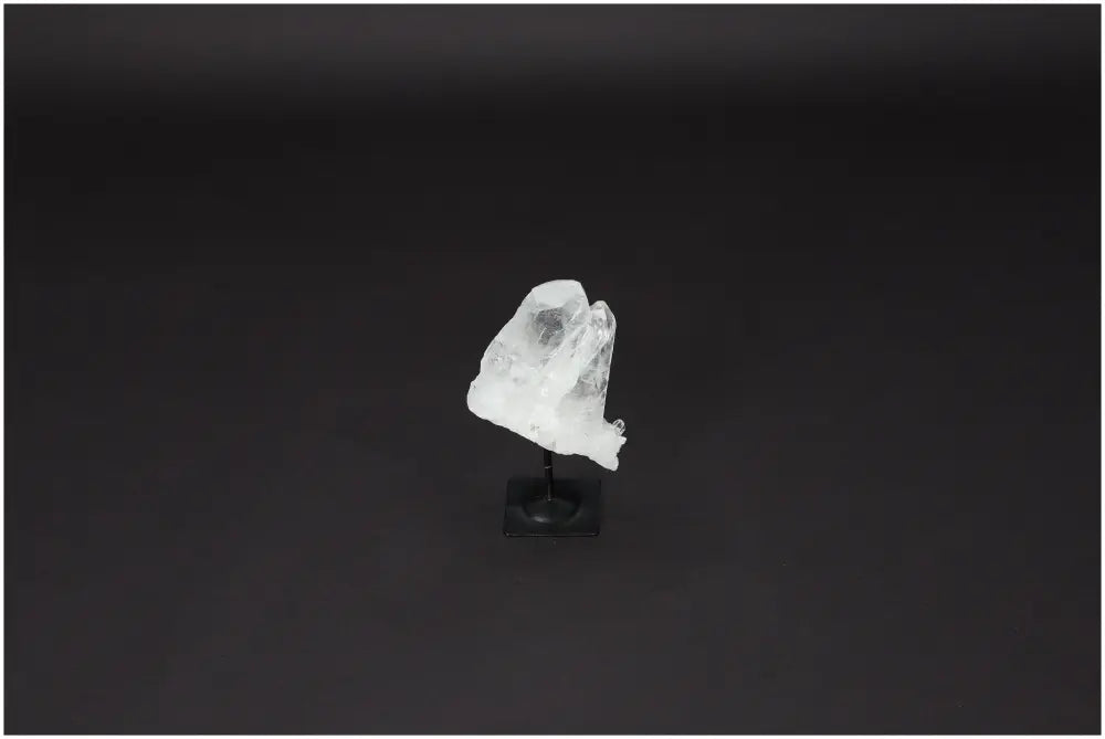 Lemurian Quartz on black metal stand, known for purification and harmonizing energies, displayed against a dark background.