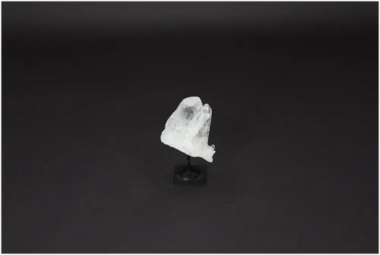 Lemurian Quartz on black metal stand, known for purification and harmonizing energies, displayed against a dark background.