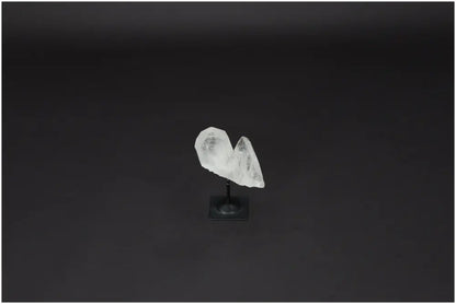 Lemurian Quartz on a metal stand, showcasing its natural clarity and purification properties against a dark background.