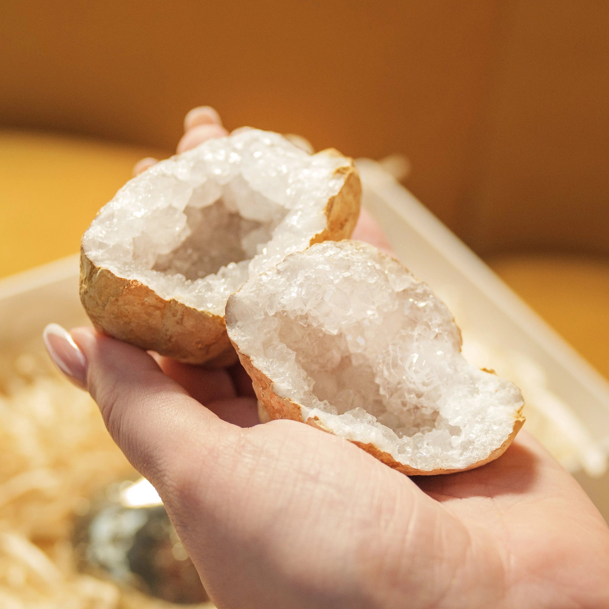 Hand holding a split geode with sparkling crystals inside, part of the Love and Wealth Gift Box from Sylvia Crystals.