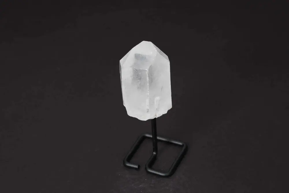 Clear quartz point with stand on black background, ideal for energy amplification and meditation. Perfect for home or office decor.