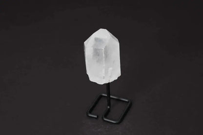 Clear quartz point with stand on black background, ideal for energy amplification and meditation. Perfect for home or office decor.
