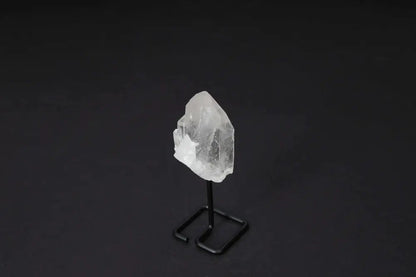 Clear Quartz Point on stand, amplifying energy and clarity, ideal for meditation and manifestation, displayed on dark background.