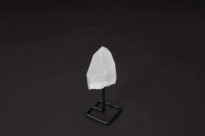 Natural Clear Quartz Point on black metal stand against dark background, showcasing its clarity and elegant finish.
