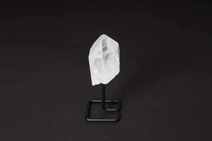 Clear quartz crystal point on a sleek black stand, known for energy amplification and clarity, ideal for meditation and energy work.