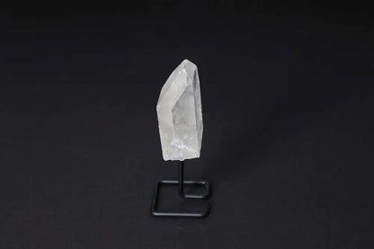 Clear Quartz Point on stand, amplifying energy for meditation and clarity, displayed against a dark background.