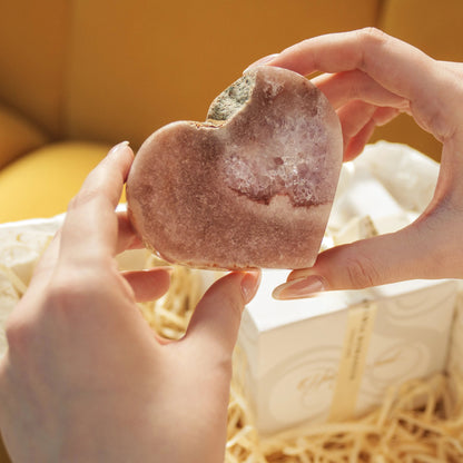 Hands holding a Pink Amethyst Heart crystal from the Now and Forever Gift Box, symbolizing love and elegance.
