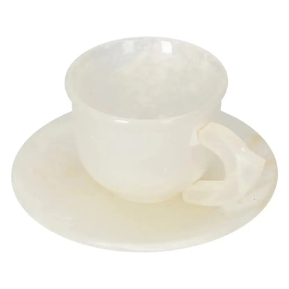 Off-white onyx coffee cup and plate set with natural variations in tone, reflecting ambient light and exuding elegance.
