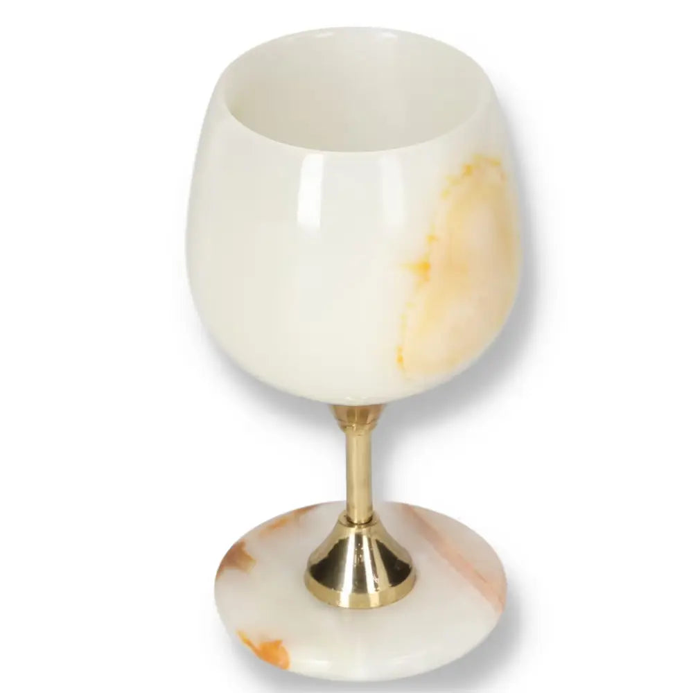 Elegant onyx wine glass with gold stem, showcasing unique veining and a polished off-white finish, perfect for fine dining occasions.